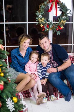 Mutlu aile Noel ağacı yakınındaki. Ebeveynler ve eğleniyor ve birlikte Noel ağacının yanında oynayan iki küçük çocuklar