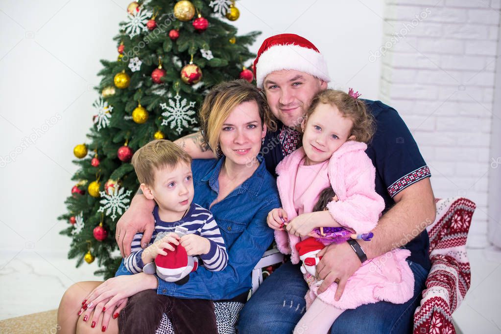 Happy family near christmas tree. Parents and two little children having fun and playing together near Christmas tree