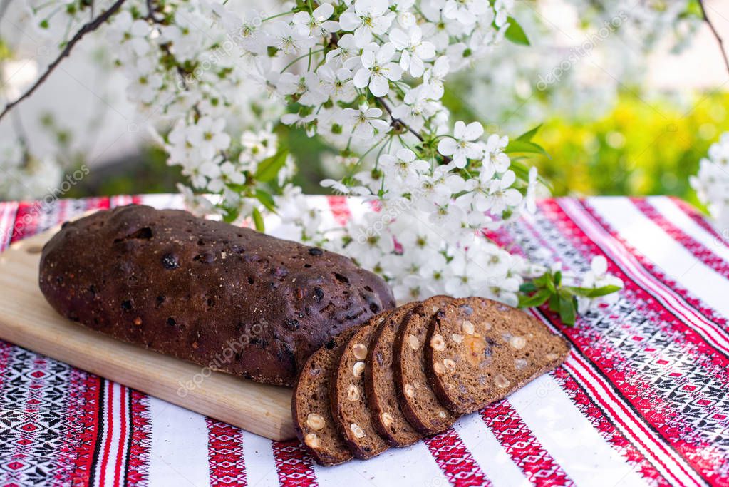 Rye bread on a wooden board against a background of with blooming cherry branches. fresh bread on a background of flowering trees