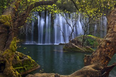 Kursunlu Tabiat Parkı'nda derin yeşil ormanda zümrüt suyun üzerinde ahşap bir çerçeve içinde fotoğraflanan güzel şelaleler, Antalya, Türkiye
