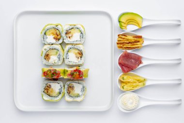 Beyaz arka planda ton balığı, avokado ve Philadelphia peynirli suşi rulosu.