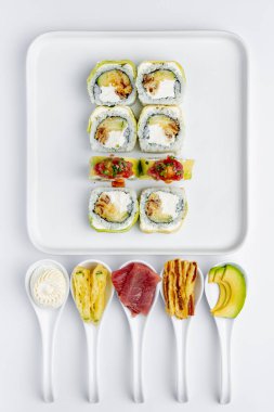 Beyaz arka planda ton balığı, avokado ve Philadelphia peynirli suşi rulosu.