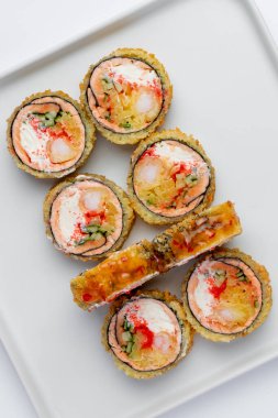 Baked sushi roll with salmon close-up on a white background isolated