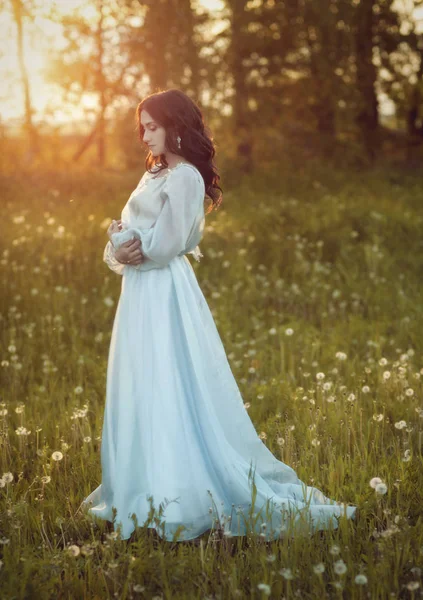 Flicka i blå klänning på ett fält av maskrosor — Stockfoto