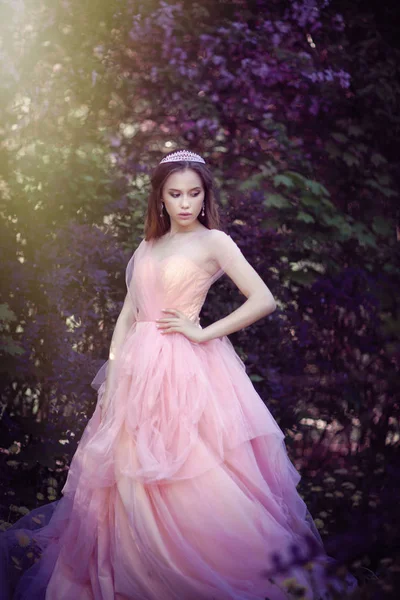 Flicka i en rosa klänning i en blomsterträdgård — Stockfoto
