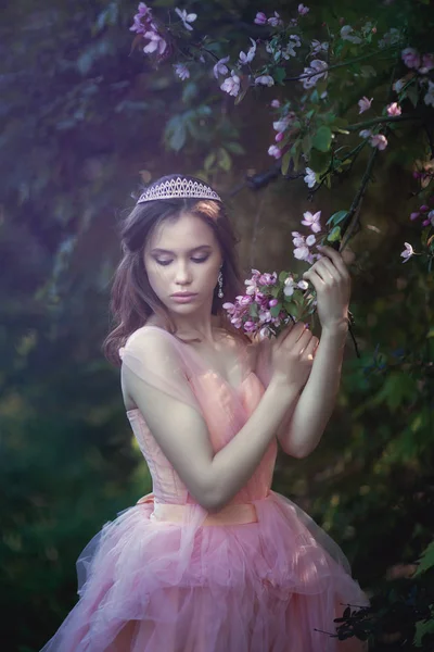 Menina em um vestido rosa em um jardim de flores — Fotografia de Stock