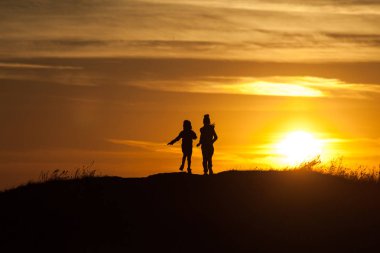 Gün batımı arka plan, bir çocuğun iki siluetleri