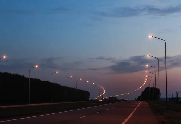 Wieczorem autostrady z latarniami światła. Droga idzie na odległość — Zdjęcie stockowe