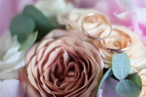 Zlaté snubní prsteny na svatební kytice růží — Stock fotografie