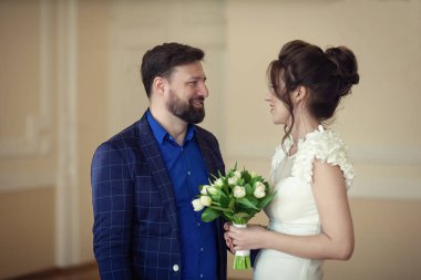 Yeni evliler. Bir mavi gömlek ve ceket bir kafes içinde damat. Beyaz Lale gelinle