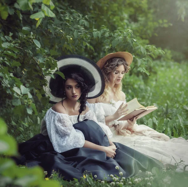 Duas meninas bonitas estão lendo um livro na natureza — Fotografia de Stock