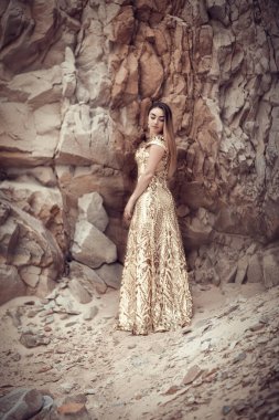 Kayaların arka planda altın elbiseli kız