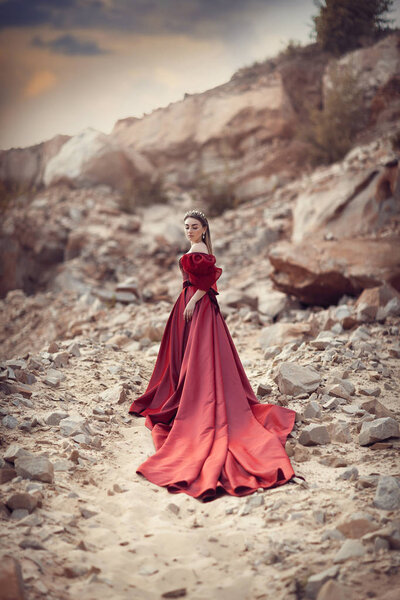 Girl in a red dress with a long skirt in the mountains