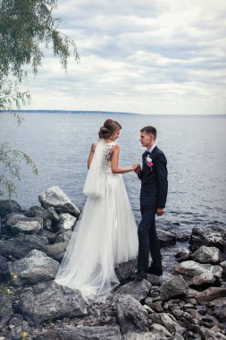 Büyük nehrin kıyısındaki taşların üzerinde bir çift genç yeni evli