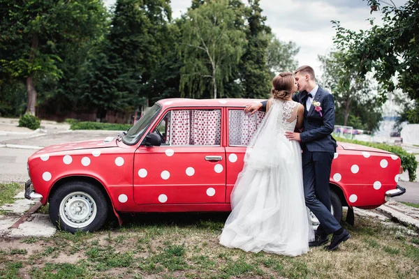 Bruid en bruidegom bij een rode retro auto — Stockfoto