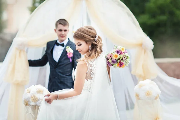 Porträtt av en ung brud och brudgum med en bukett blommor — Stockfoto