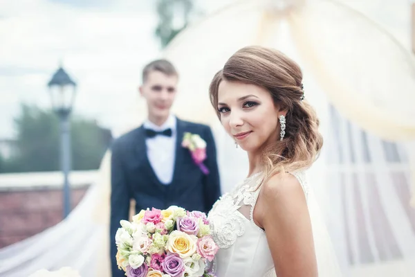 Porträtt av en ung brud och brudgum med en bukett blommor — Stockfoto