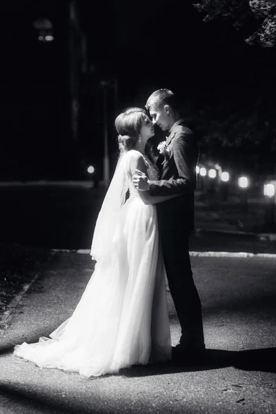 Recém-casados se beijam sob a lanterna à noite — Fotografia de Stock