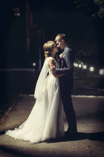 Recém-casados se beijam sob a lanterna à noite — Fotografia de Stock