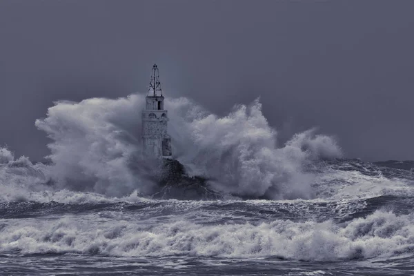 Oude vuurtoren in het midden van grote stormachtige golven. Crashen grote zee Golf tegen rotsen splash en spray. Enorme stormachtige zee Wave Splash — Stockfoto