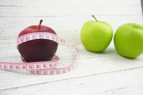 Ahşap ba üzerinde ölçüm bandı ile Yeşil ve Kırmızı Elmalar kapatın