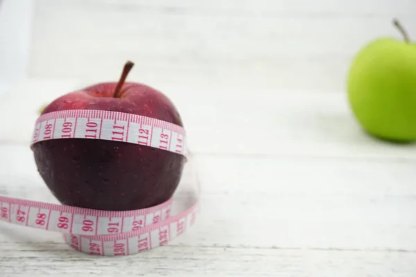 Ahşap ba üzerinde ölçüm bandı ile Yeşil ve Kırmızı Elmalar kapatın