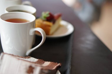 Çikolatalı Kek ve peynirli kek ve çilekli kek. Akşam İngiliz çay saatinde bir fincan çay. Seçici odaklama  