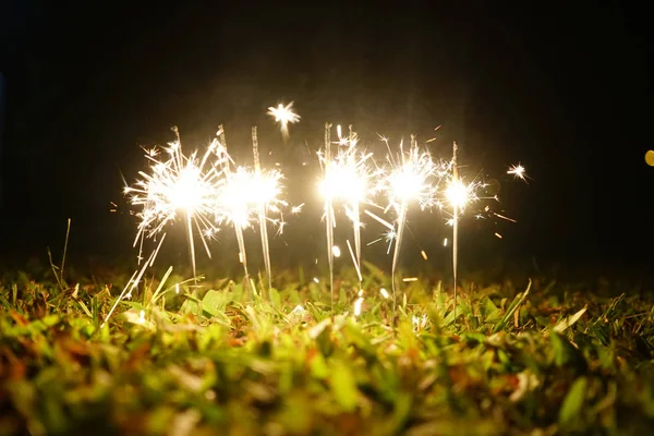 新年のパーティースパークル火災は 地面の草の上に燃えます 選択フォーカス — ストック写真