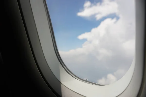 Plane window view with blue sky and sea