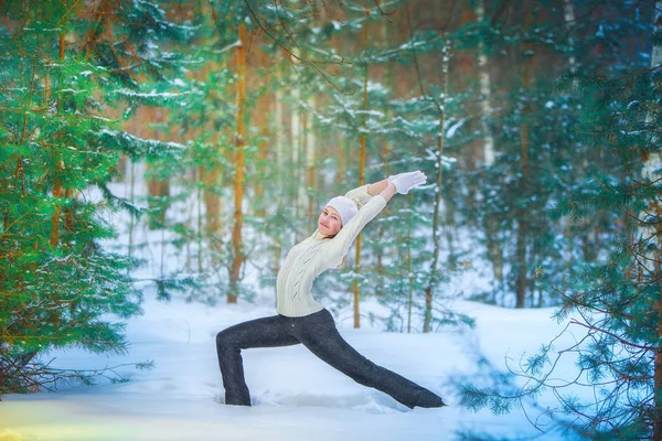 beautiful woman doing yoga outdoors in the snow in yellow T-shirt