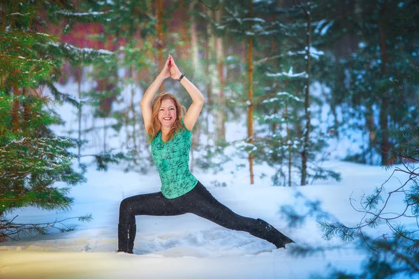 beautiful woman doing yoga outdoors in the snow in yellow T-shirt