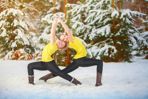 两位美女在户外在雪地里做瑜伽 — 图库照片