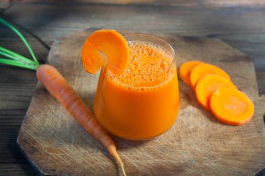 Ahşap masada bardakta havuç suyu.