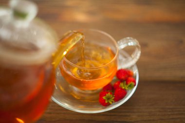 bir tabloda bir güzel cam kase lezzetli yabani çilek çay