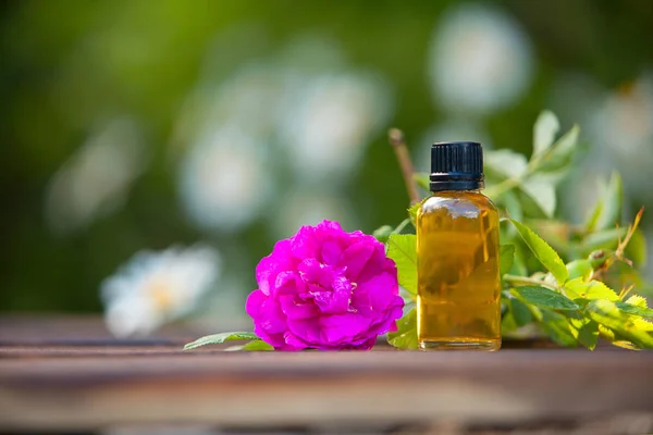 Esencia de flores en la mesa en un hermoso frasco de vidrio — Foto de Stock