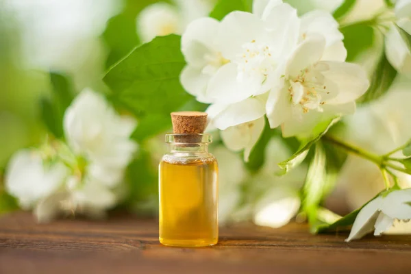 Esencia de flores sobre fondo de madera en hermoso frasco de vidrio — Foto de Stock