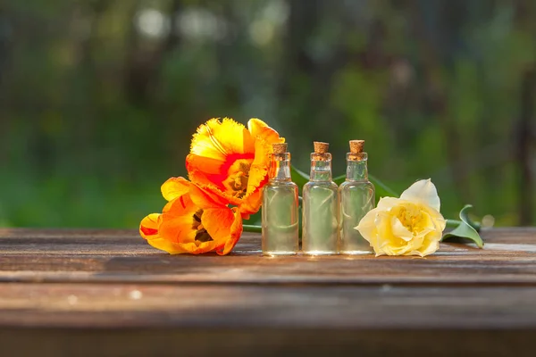 Esencia de flores en la mesa en un hermoso frasco de vidrio — Foto de Stock