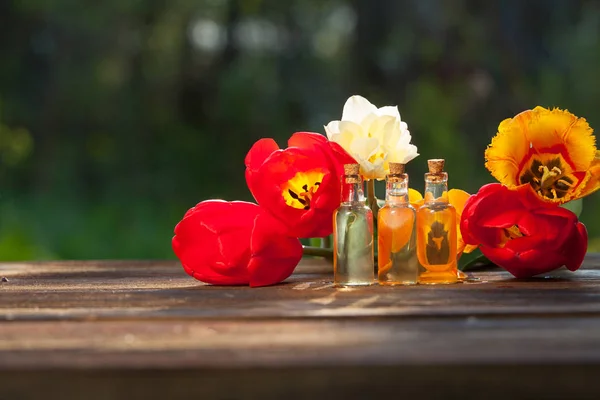 Esencia de flores en la mesa en un hermoso frasco de vidrio — Foto de Stock