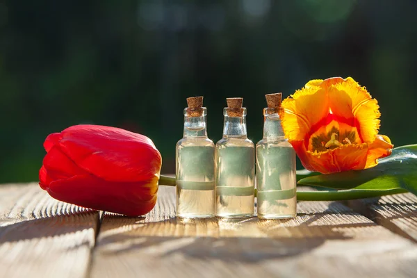 Esencia de flores en la mesa en un hermoso frasco de vidrio — Foto de Stock