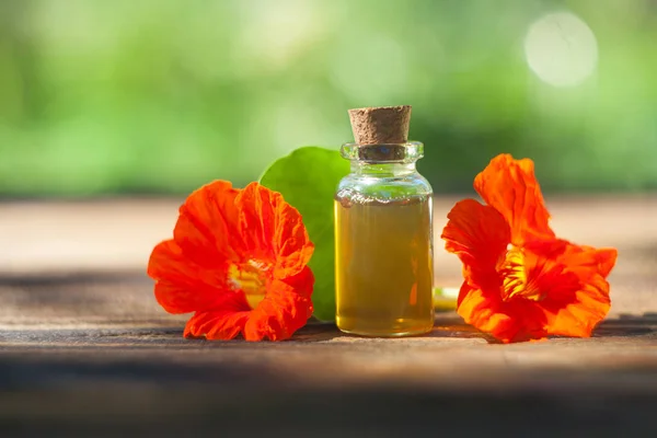 Aceite esencial de capuchina en una hermosa botella sobre fondo de madera — Foto de Stock