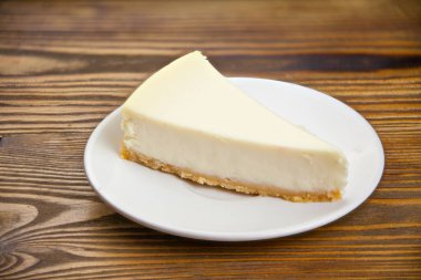 ahşap masa üzerinde beyaz tabakta klasik cheesecake