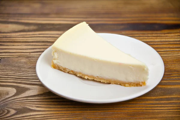 Klasický cheesecake na bílém štítku na dřevěný stůl — Stock fotografie