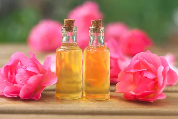 Esencia de rosa en la mesa en una hermosa botella de vidrio — Foto de Stock