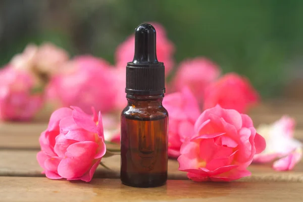 Esencia de rosa en la mesa en una hermosa botella de vidrio — Foto de Stock