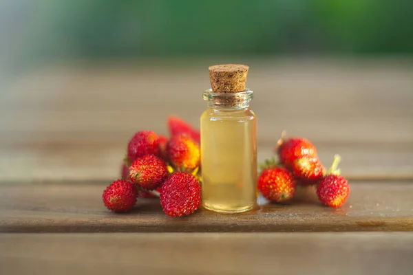 Esencia de fresa silvestre en la mesa en un hermoso frasco de vidrio — Foto de Stock