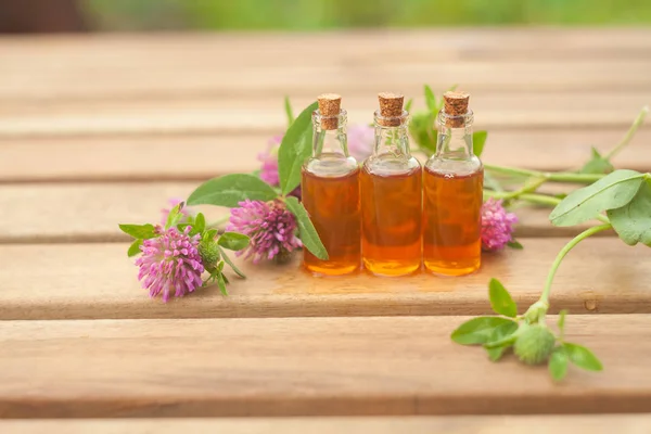 Esencia de flores en la mesa en un hermoso frasco de vidrio — Foto de Stock