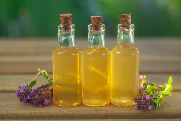 Aceite esencial de tomillo en una hermosa botella en la mesa — Foto de Stock