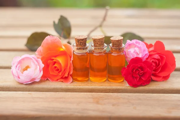Esencja róży na stole w pięknej szklanej butelce — Zdjęcie stockowe