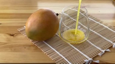 Şeffaf bardakta taze sıkılmış mango suyu.