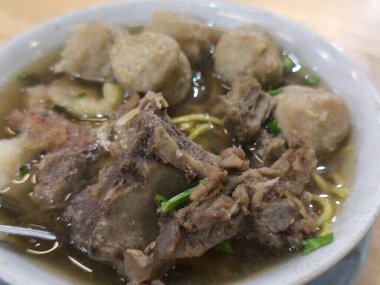 Lezzetli bir kase bakso çorbası. İçinde taze sığır pirzolası, baharatlı şehriye ve lezzetli köfteler var. Yeşilliklerle süslenmiş, doyurucu yemekler.